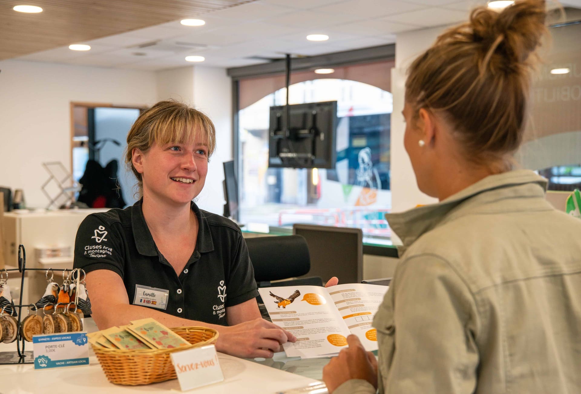 Femme à l'accueil qui montre un endroit sur une carte à une touriste